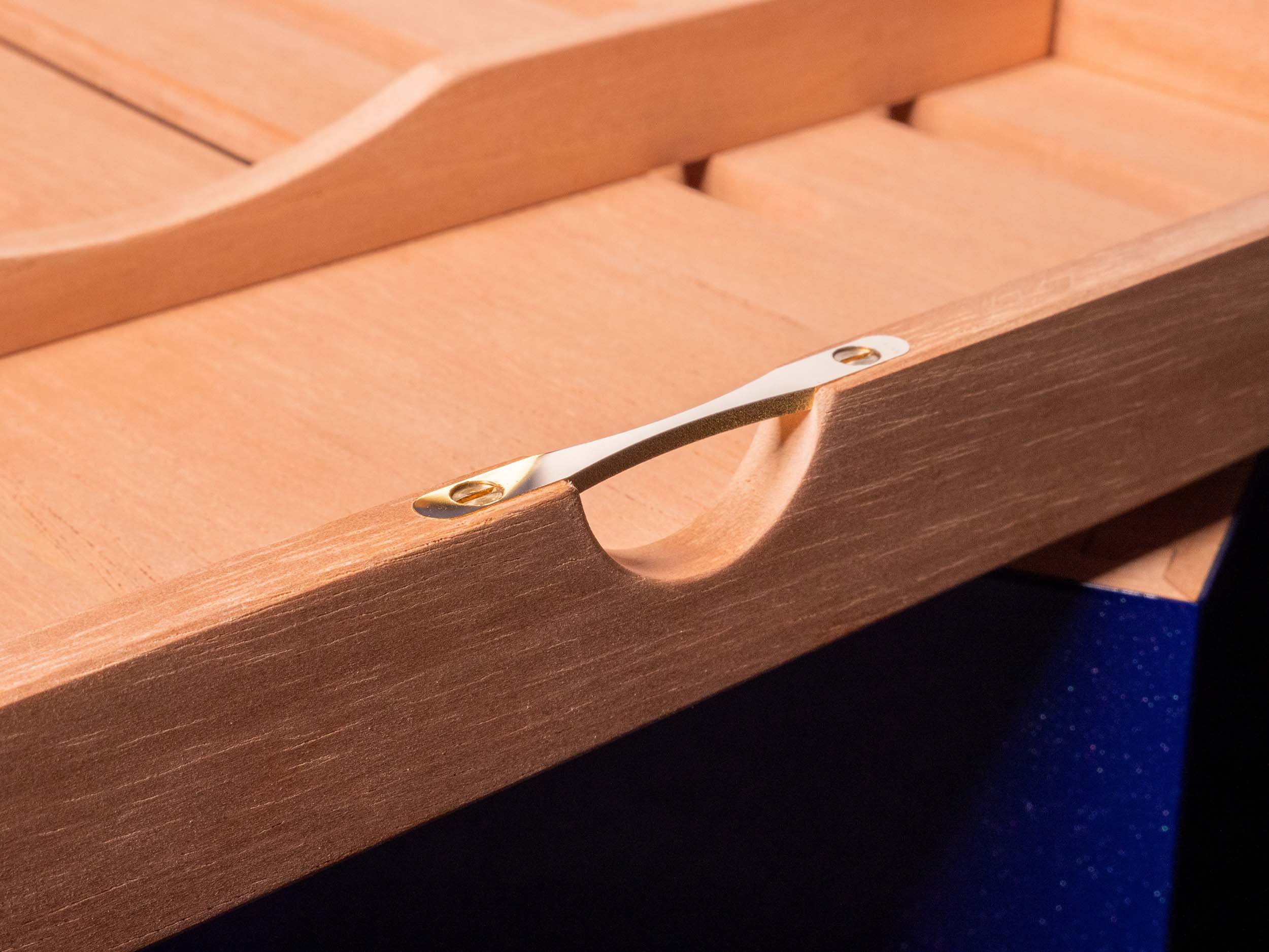A Spanish-cedar tray with a brass handle and polished screws, empty.