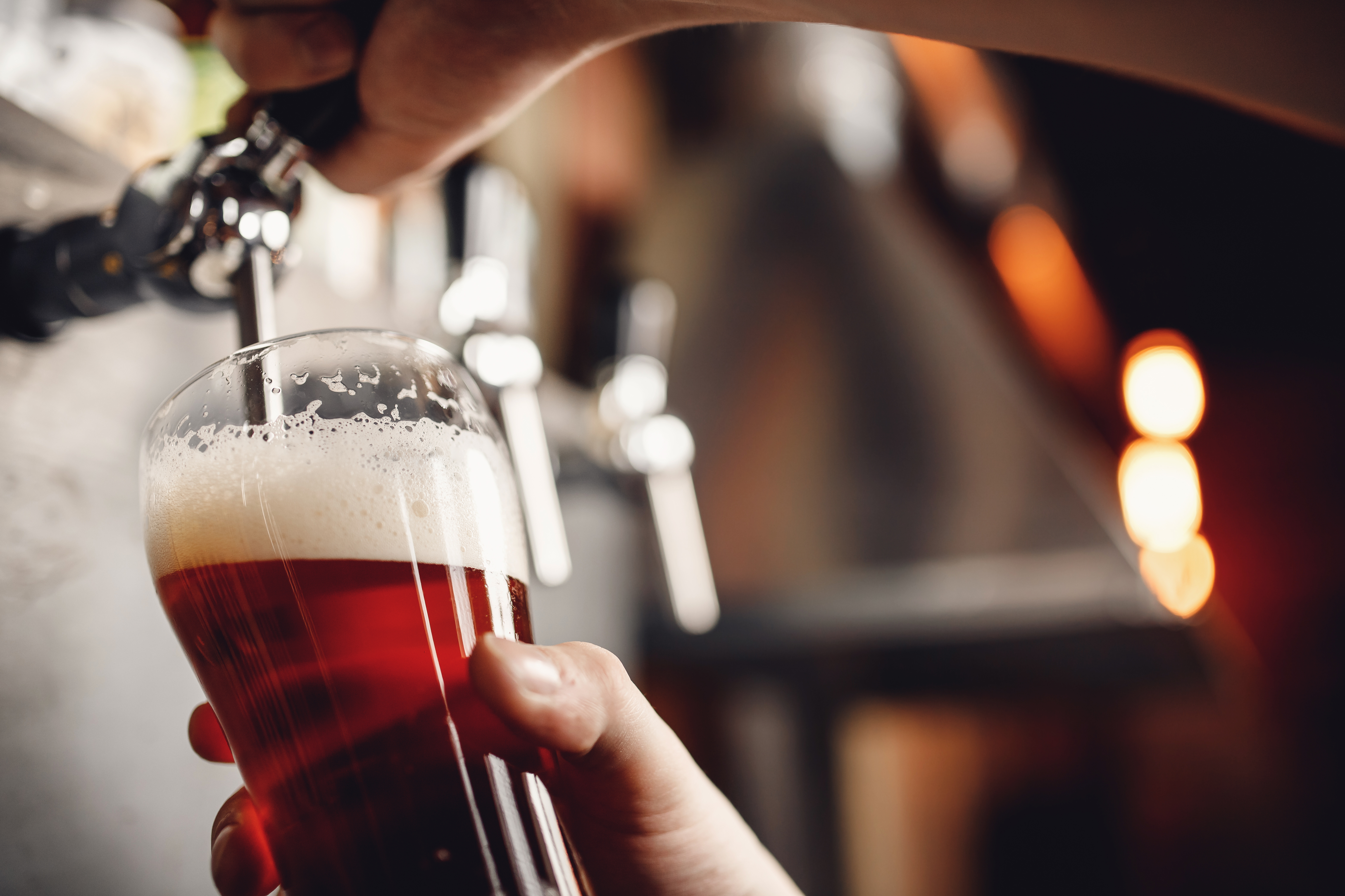 Amber beer poured from a tap into a tulip glass.