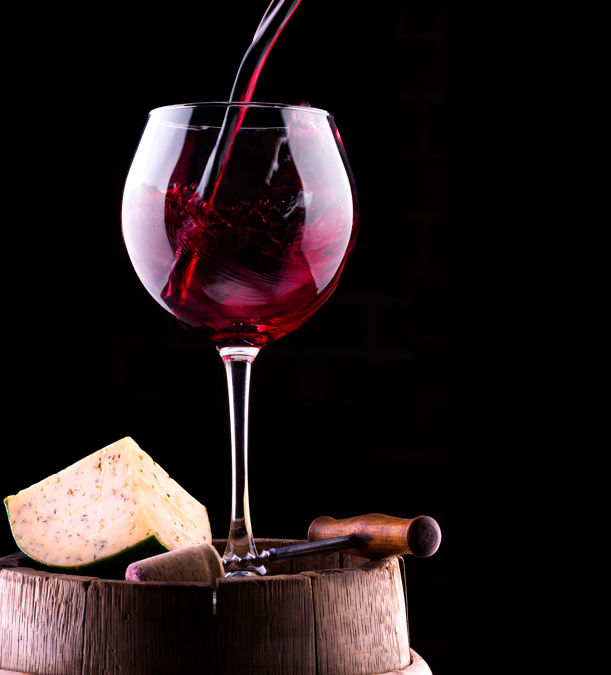 Red wine poured into a glass on a barrel head.