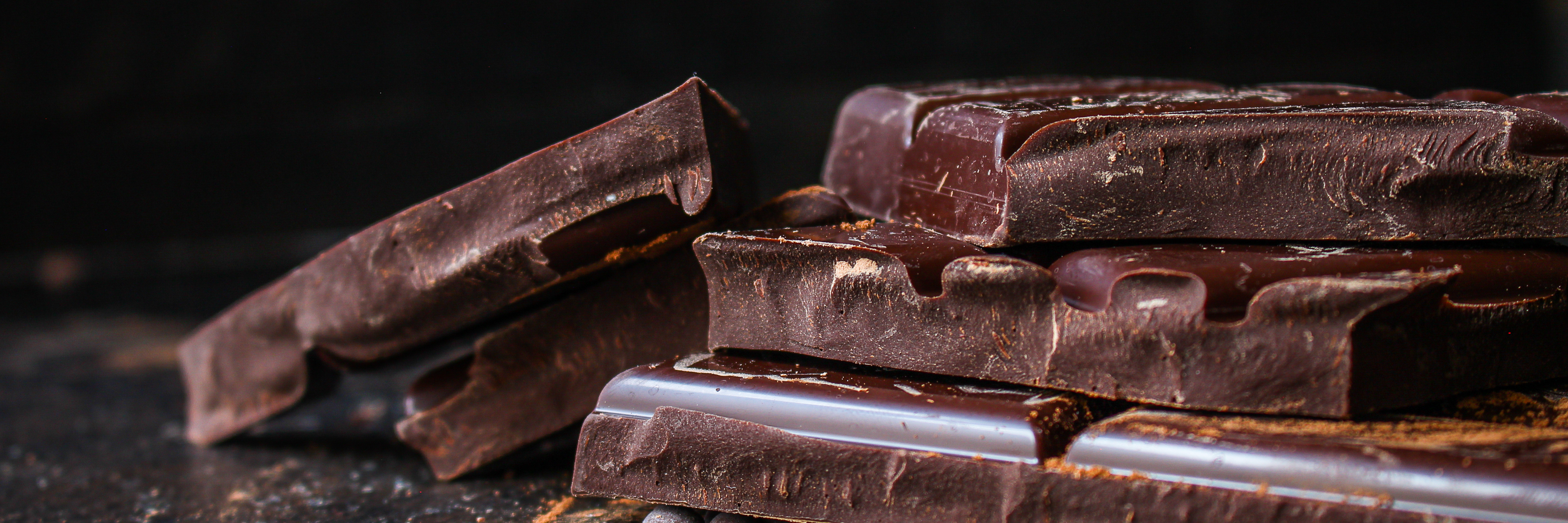 Broken slabs of dark chocolate on a dark surface.